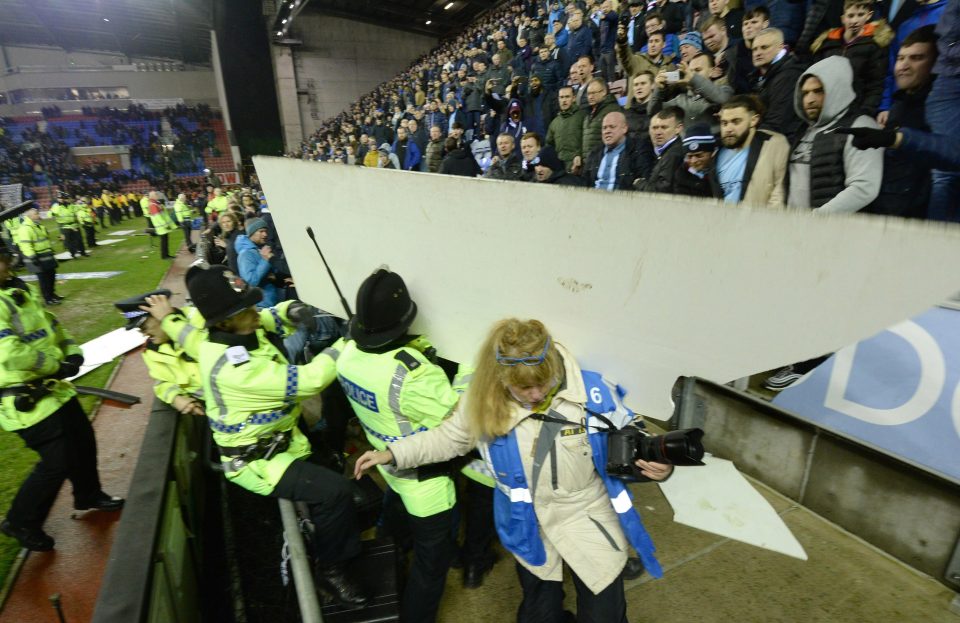  A board thrown from the away section strikes a police officer