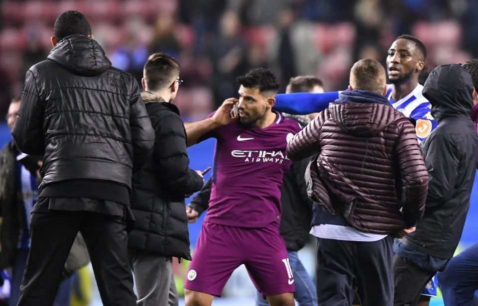  The Manchester City striker is held back as he is swamped by Wigan fans