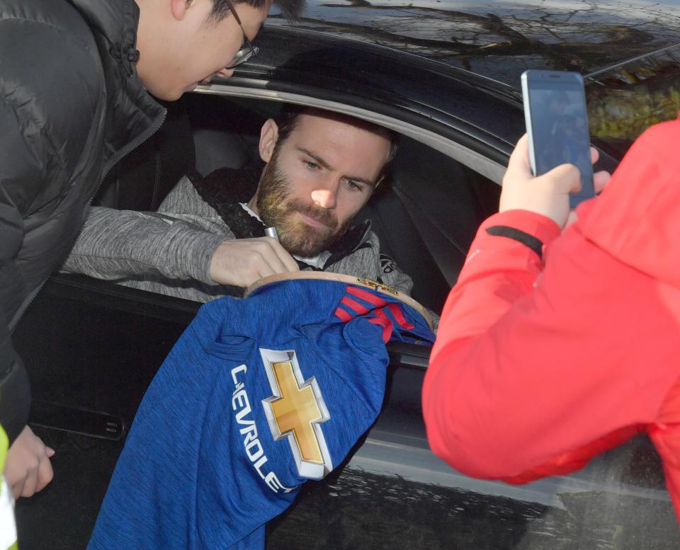  Juan Mata takes the time to sign a shirt on his way into training