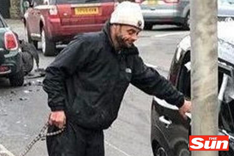  The troubled TV star, holding his dog on a lead, places a hand on his wrecked Mini