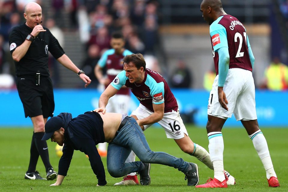  West Ham skipper Mark Noble clashes with a fan during this afternoon's pitch invasion at the London Stadium