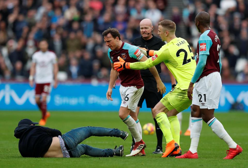  Joe Hart jumps in and pulls Mark Noble away from pitch invader.