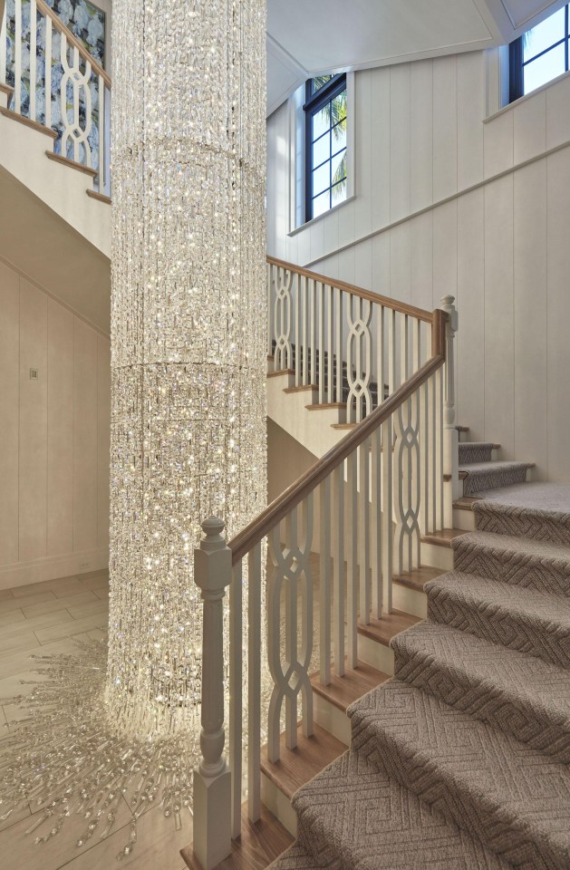 The soaring staircase is lit up by the stunning three-storey Swarovski crystal chandelier