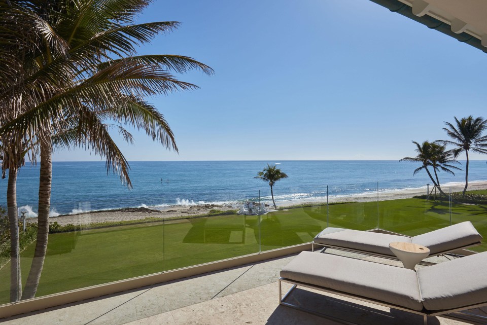 A balcony attached to the mansion overlooks the blue skies and ocean