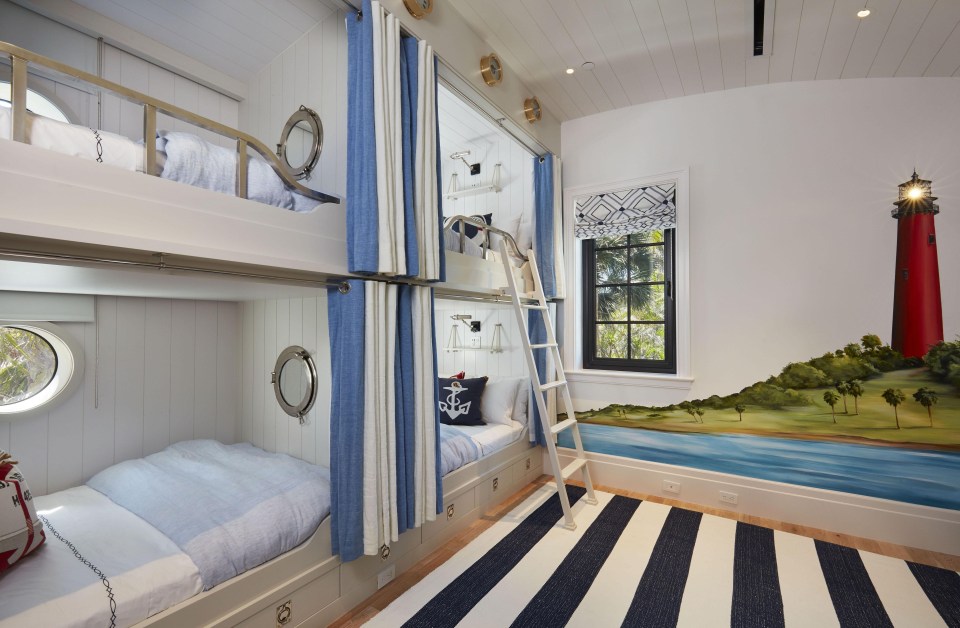 Two bunk beds are placed side-by-side in one bedroom with a lighthouse painting on the wall