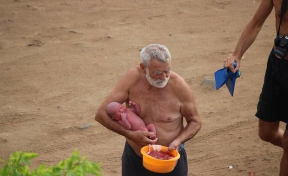 A man believed to be a doctor carries the child after the birth 