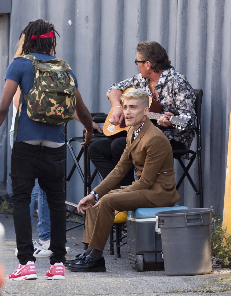 Zayn perched on a cool box while filming his new music video