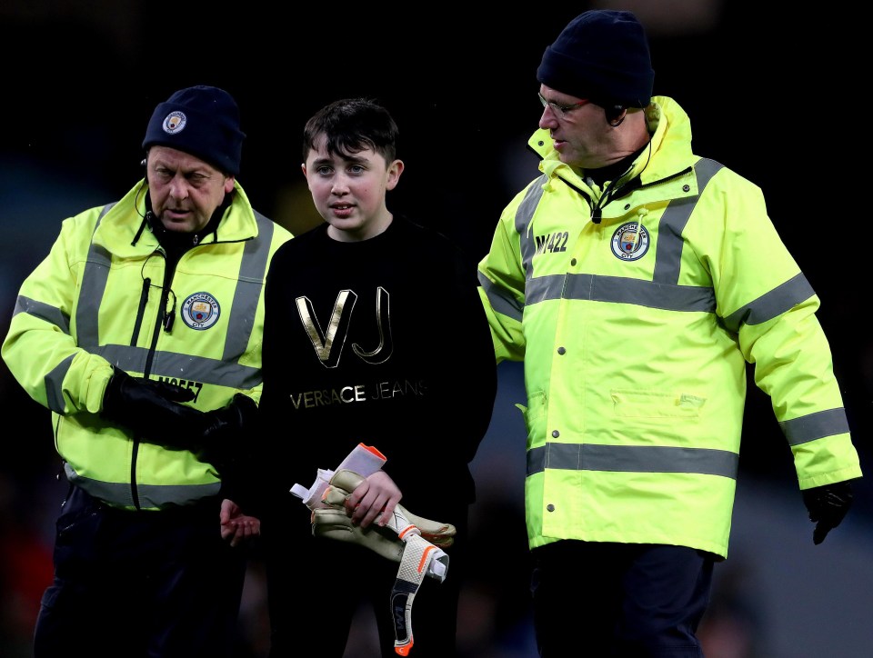 The fan is escorted off by stewards - clutching the gloves of Argentina and Chelsea stopper Willy Caballero