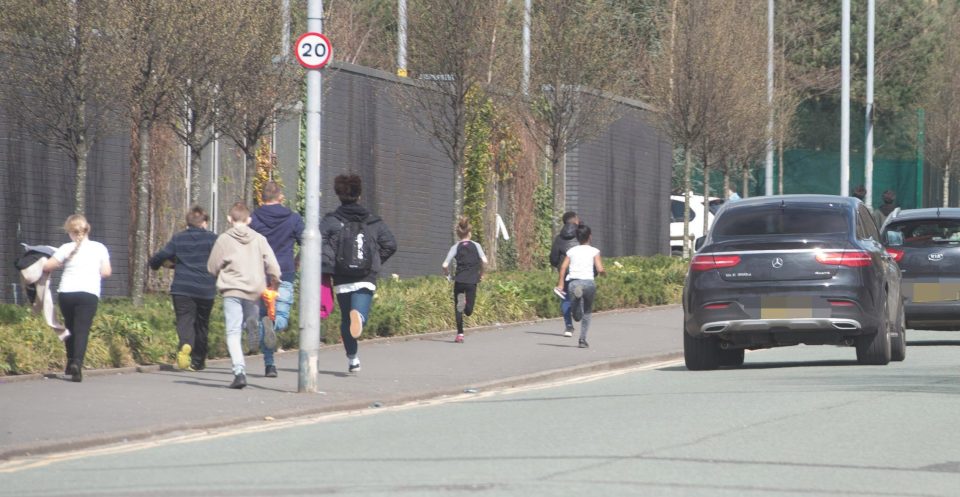  Youngsters run down the street after spotting the Mercedes of City star Bernardo Silva