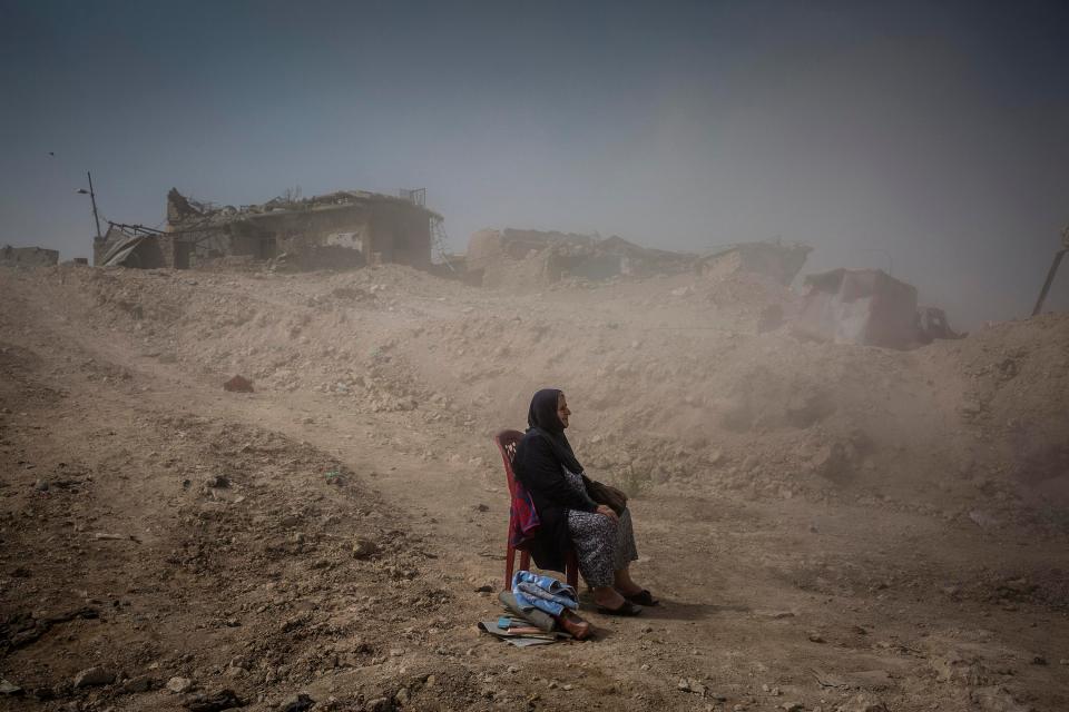  A woman looks on as Iraqi Civil Defence workers excavate the remains of her sister and niece from her house