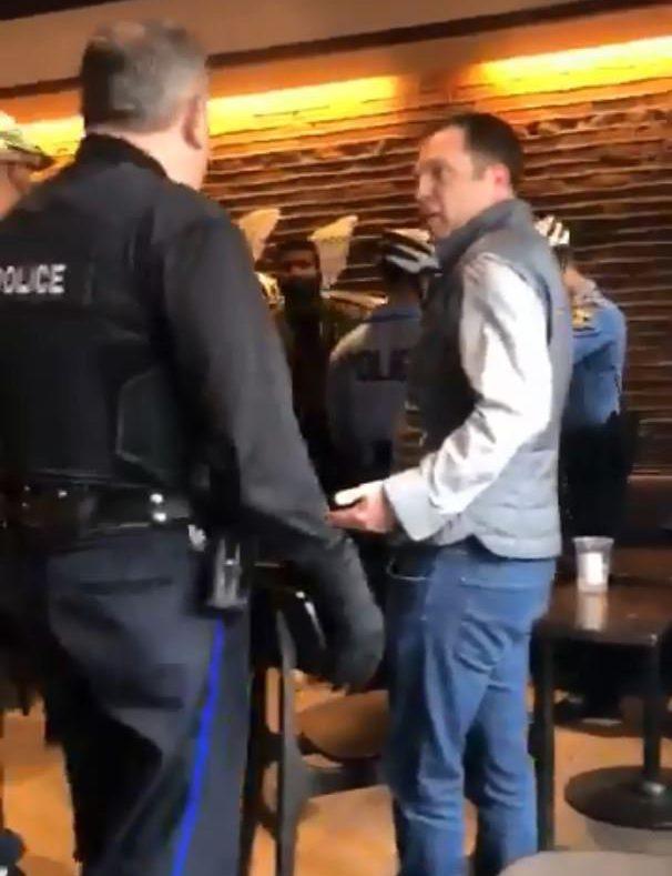  Police officers speak to customers as the two men are handcuffed