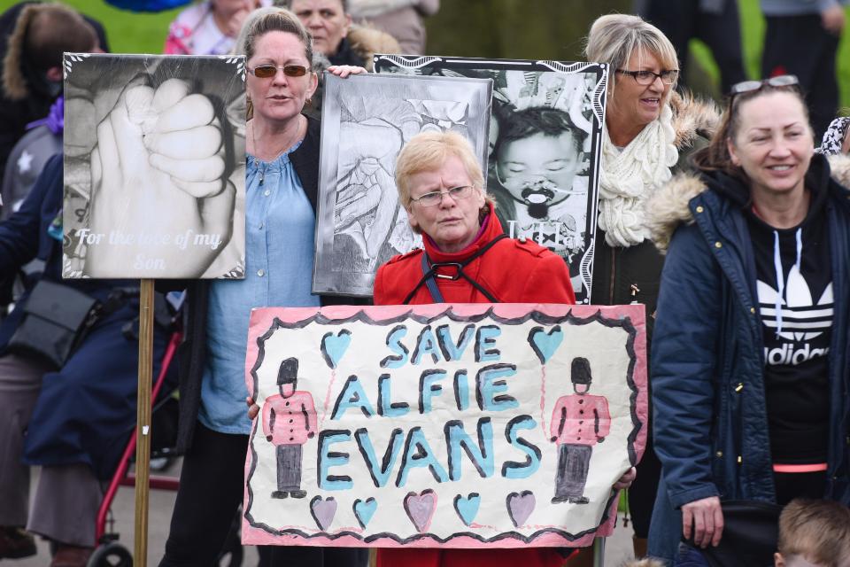 Demonstrators hold up handmade signs while gathering outside the hospital 