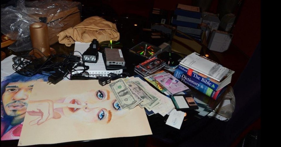 A dictionary, dollar bills, and drawings are among the items on one of his desks