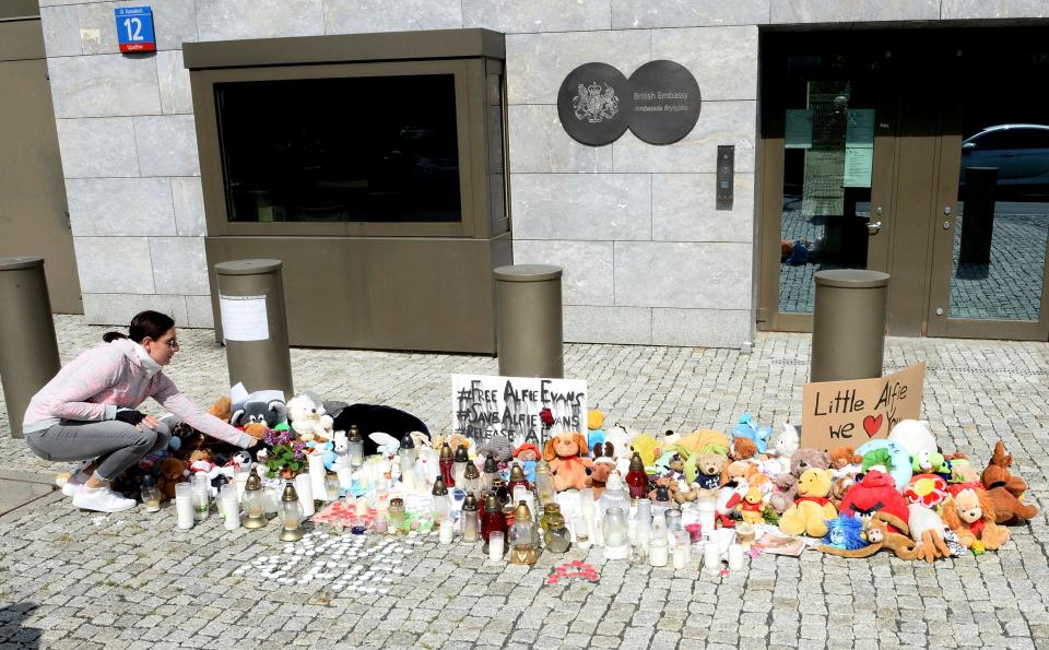  A woman lays flowers for terminally ill British toddler Alfie Evans placed outside the British Embassy in Warsaw, Poland