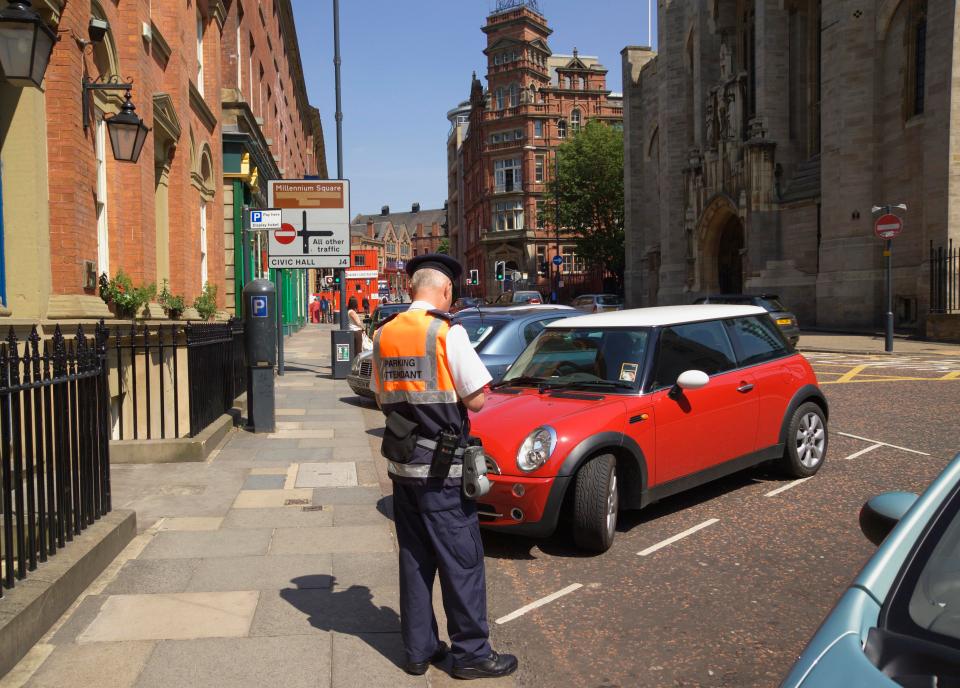 A traffic warden writing a motorist a ticket in Leeds