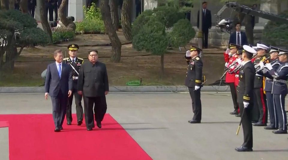  Moon grasped Kim's hand and led him along an blindingly red carpet into South Korean territory