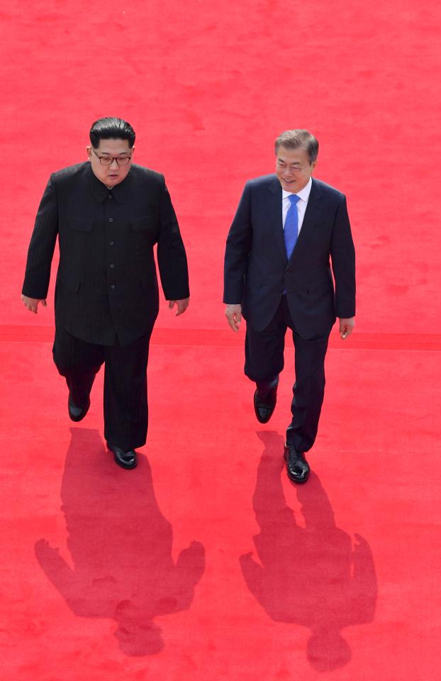  Kim wore his trademark black Mao suit as he walked down a glowing red carpet with his rival Moon