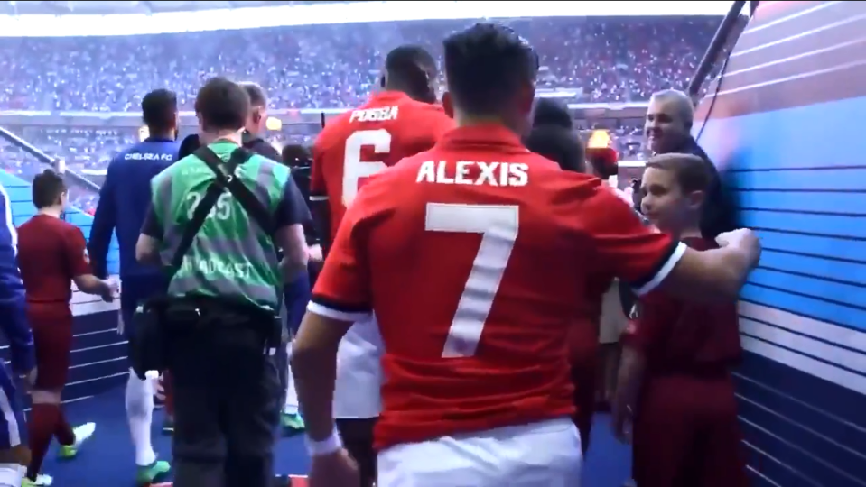  Alexis Sanchez walks onto the pitch with a new ballboy