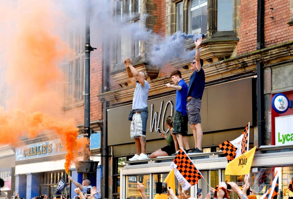  Fans look for any vantage point to join in the fun whilst one supporter let off a gold flare