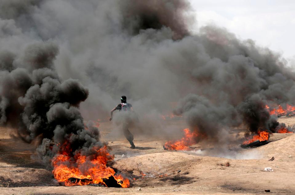  A protester runs between the flaming tyres amid clashes on the border