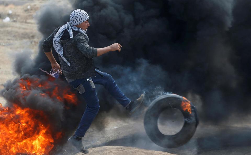  A protester kicks a burning tyre during anti-Israel protests in Gaza today