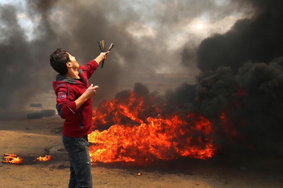  A Palestinian protester fires rocks towards the Israeli border with a slingshot