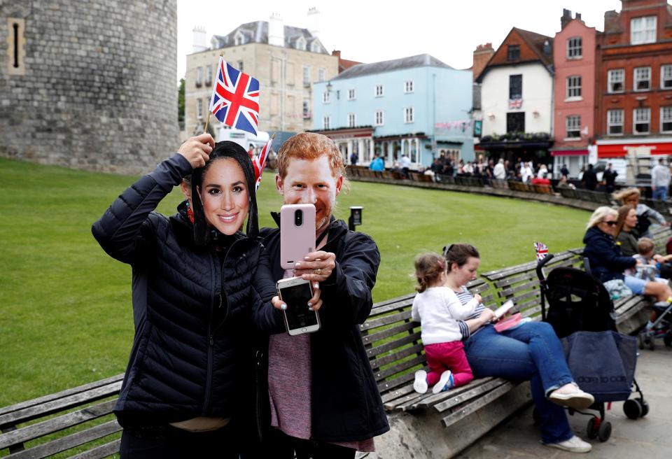 Some fans pose with Meghan and Harry masks in front of Windsor Castle