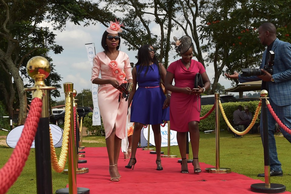 Three ladies walk a red carpet to watch the Royal Wedding in Kenya