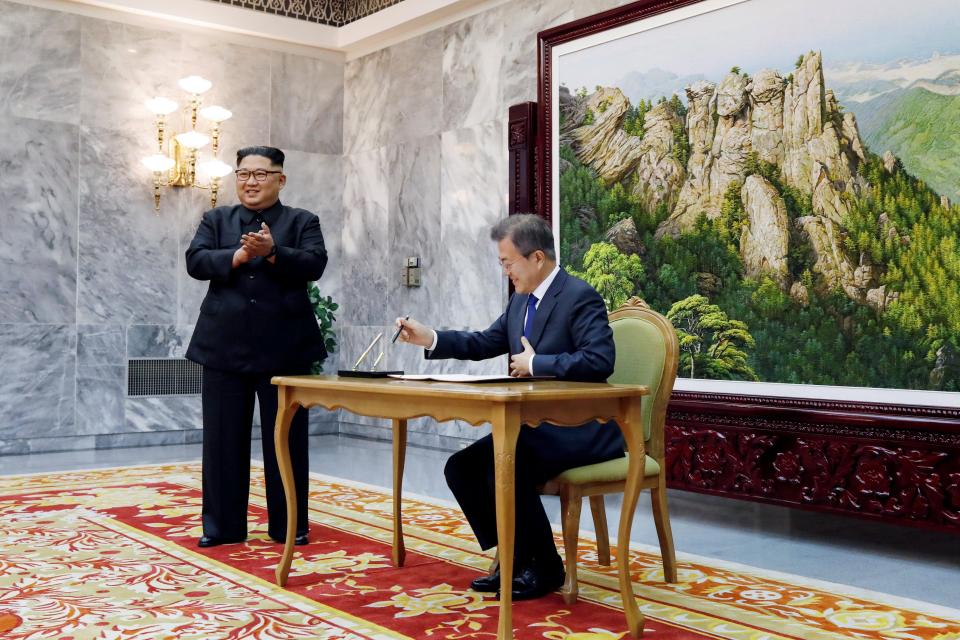  South Korean President Moon Jae-in signs a guestbook as North Korean leader Kim Jong-un reacts before their summit at the truce village of Panmunjom