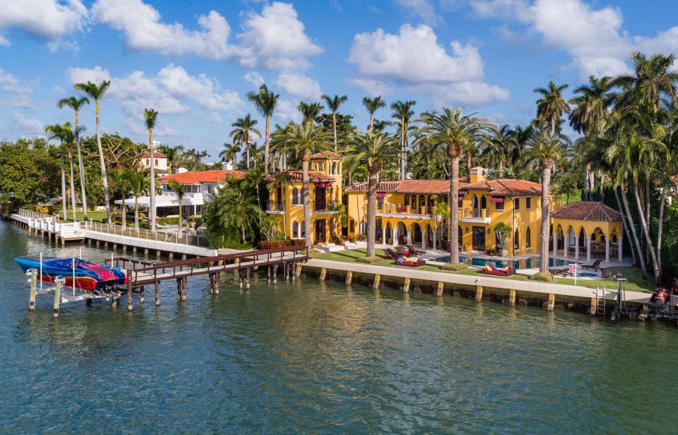  The mansion is surrounded by palm trees and has a dock at the back