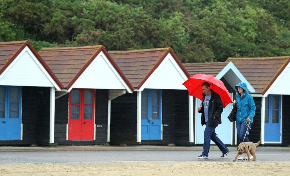  People walk their dog in the rain on Bournemouth beach in Dorset