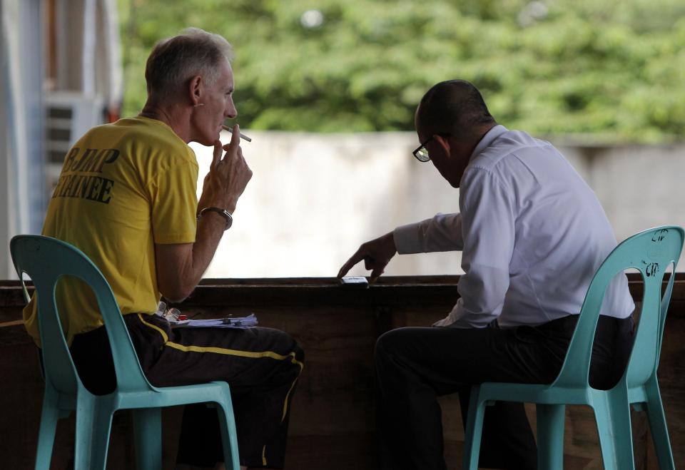  The evil rapist smokes a cigarette as he chats with his lawyer outside the court