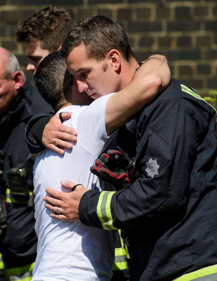  Firefighter comforts survivor after terrifying blaze which claimed 72 lives