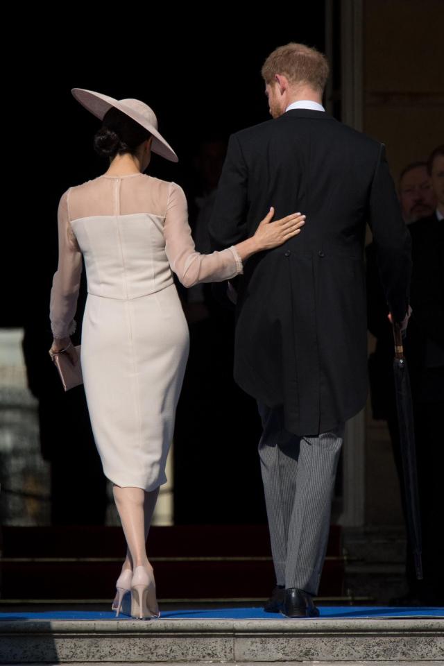  Meghan placed a hand on Harry's back as they attended Prince Charles' birthday garden party