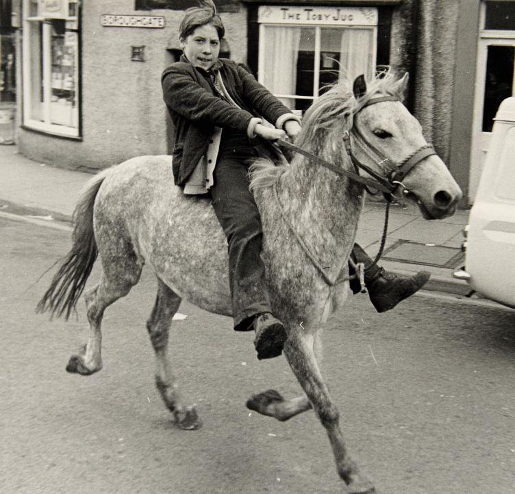  A young boy rides his horse through the Cumbrian market town in this undated black-and-white photograph