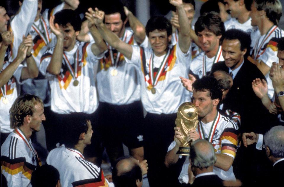  Lothar Matthäus kisses the World Cup trophy as Andreas Brehme looks on