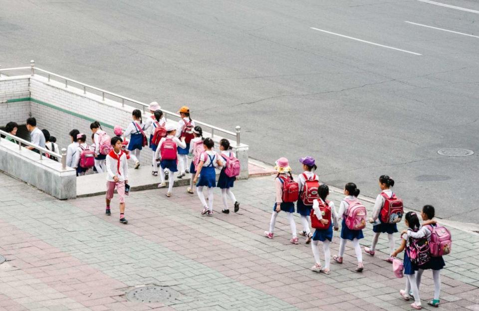  A group of brightly dressed school children enter a train station