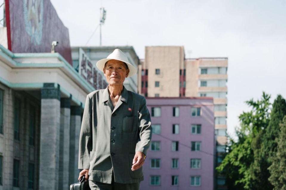  A man in North Korea walks against a colourful backdrop