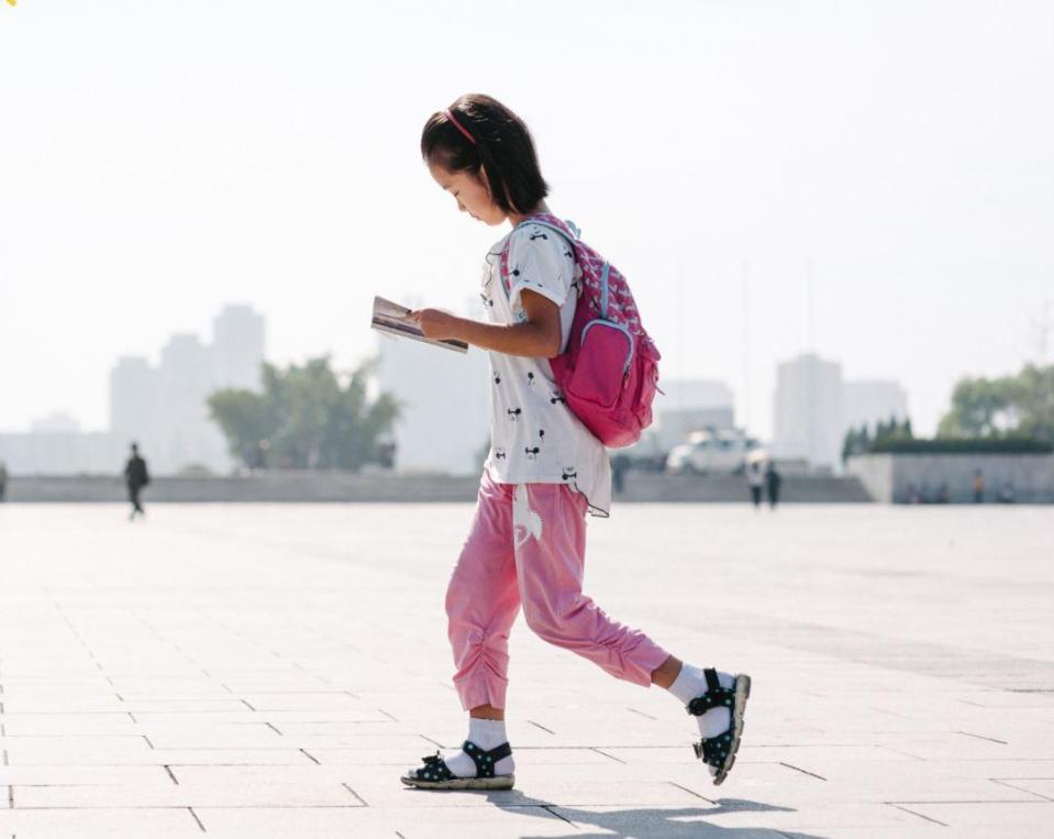  A child reads as she walks through the city in North Korea