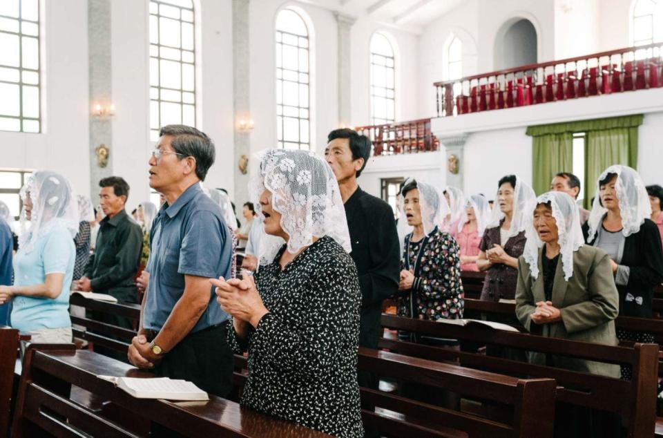  Veiled women and men appear to sing at a church service in North Korea