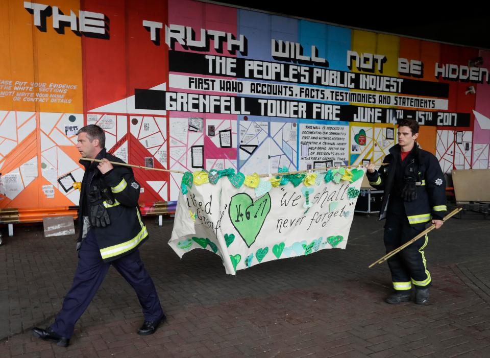  Fire fighters carry a banner in support of those affected by the tragedy