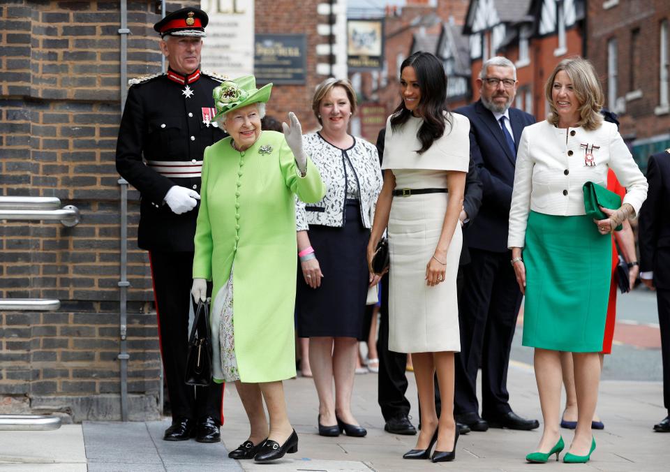  Meghan watches as the Queen gives her signature wave