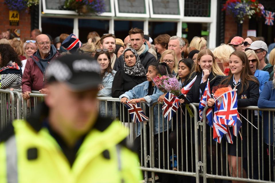  People eager to catch a glimpse of The Queen and Meghan hung over metal barriers