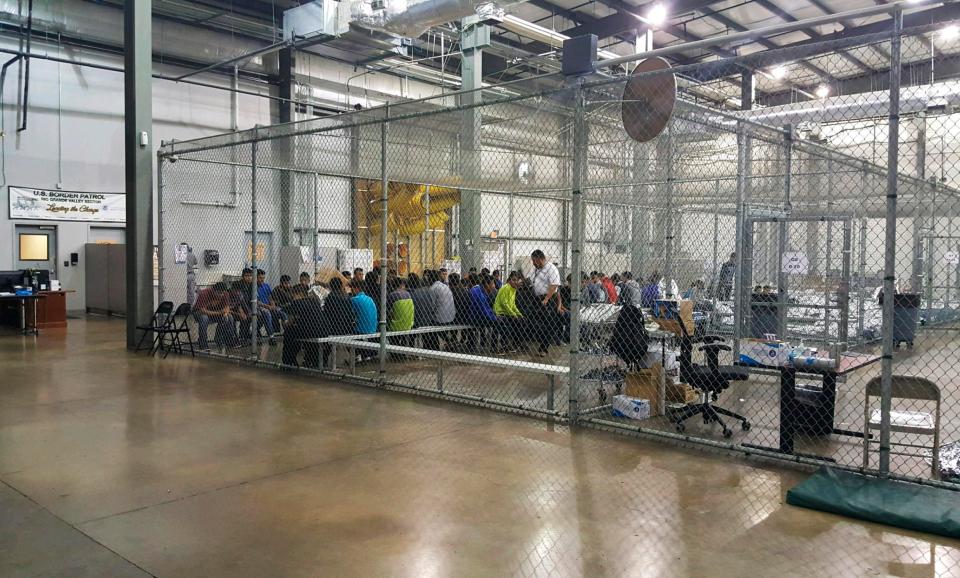  Migrants sit in one of the cages at a facility in McAllen, Texas