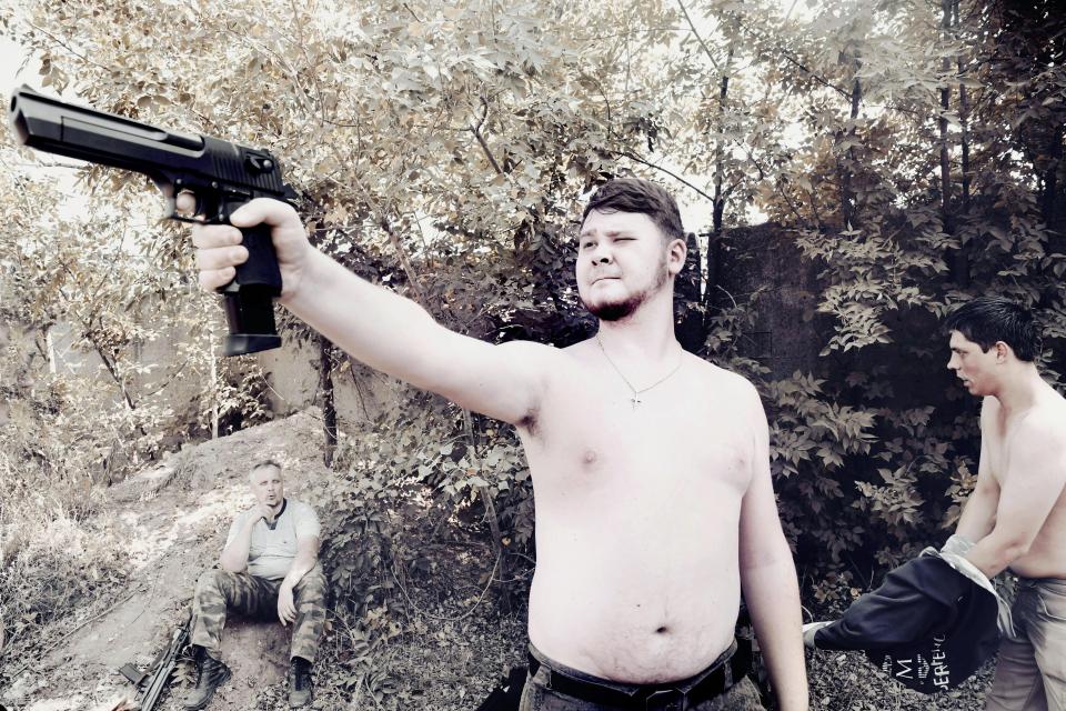  A young man plays with a pistol during a life-size military game imitating the war in Syria