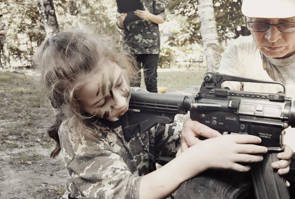  A young Ukrainian girl trains with a weapon at a paramilitary youth group