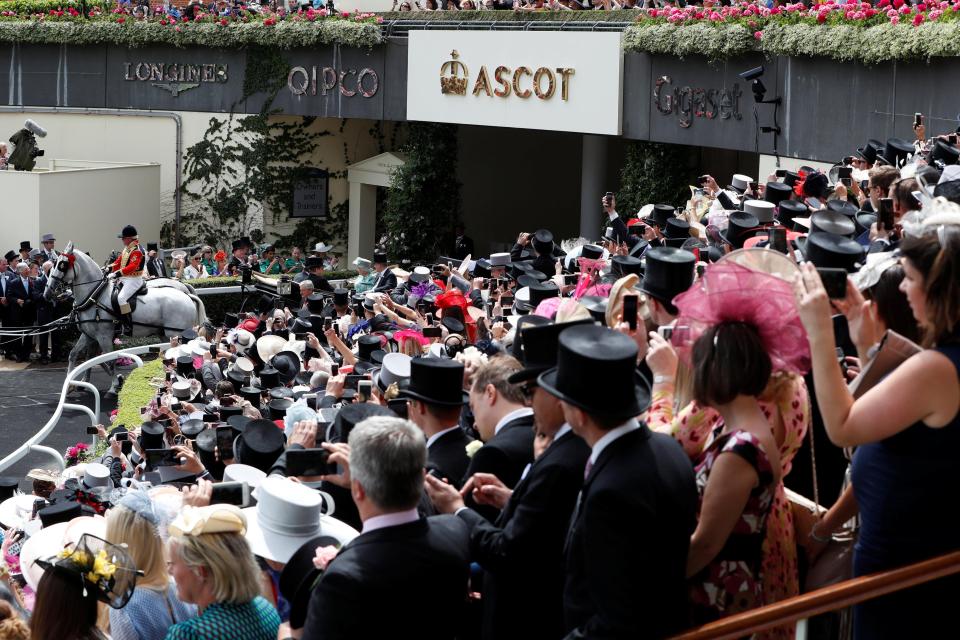  Crowds cheer as the Queen is carted out onto the course