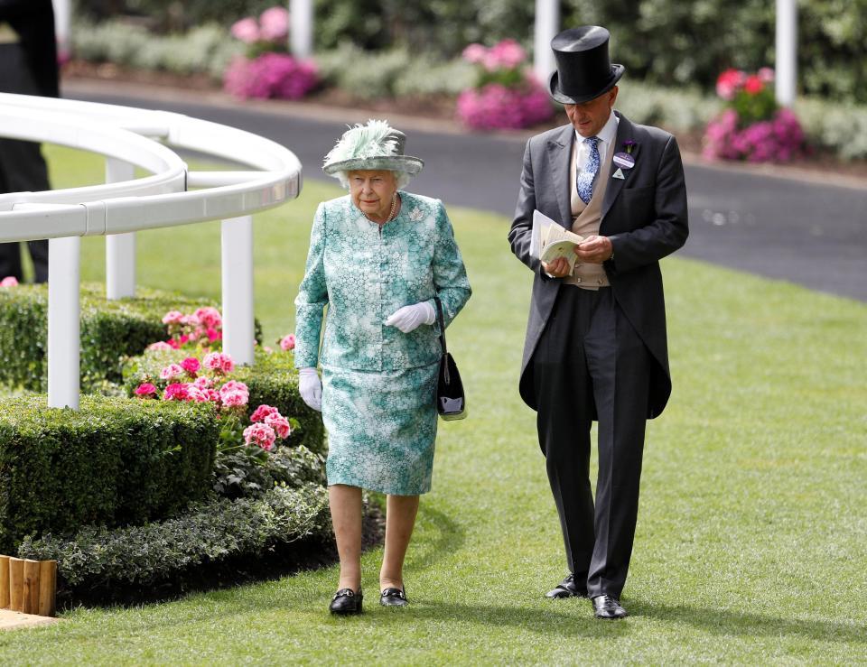  The Queen is accompanied on her way to the Royal pavilion before the start of racing