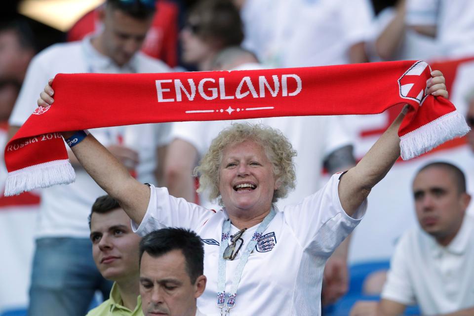 A woman holds aloft and England scarf in the stands with kick-off approaching