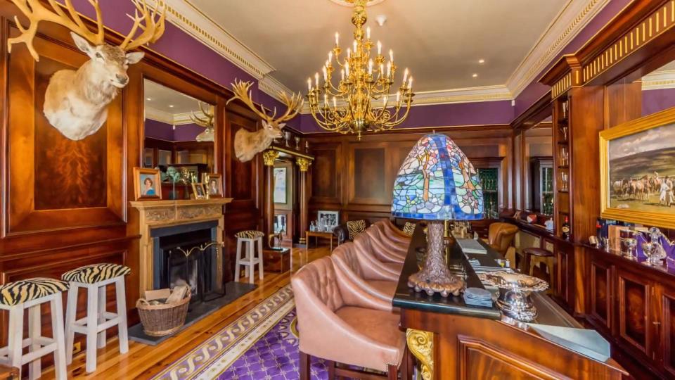  Stag heads hang from the wall in a wood-panelled room that features a bar